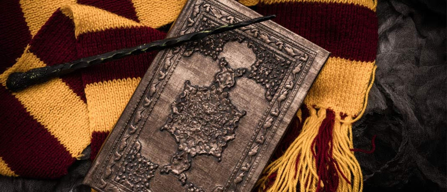 Zauberstab und Buch auf Gryffindor-Schal