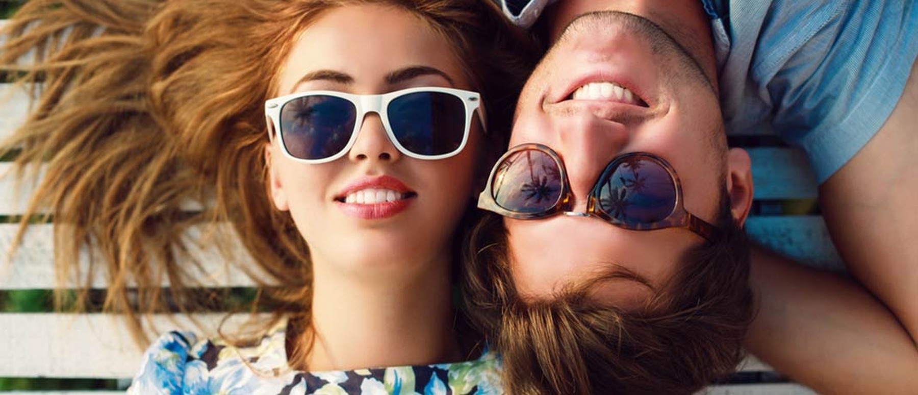 Lächelnde Paare mit Sonnenbrillen liegt auf einem Liegestühl